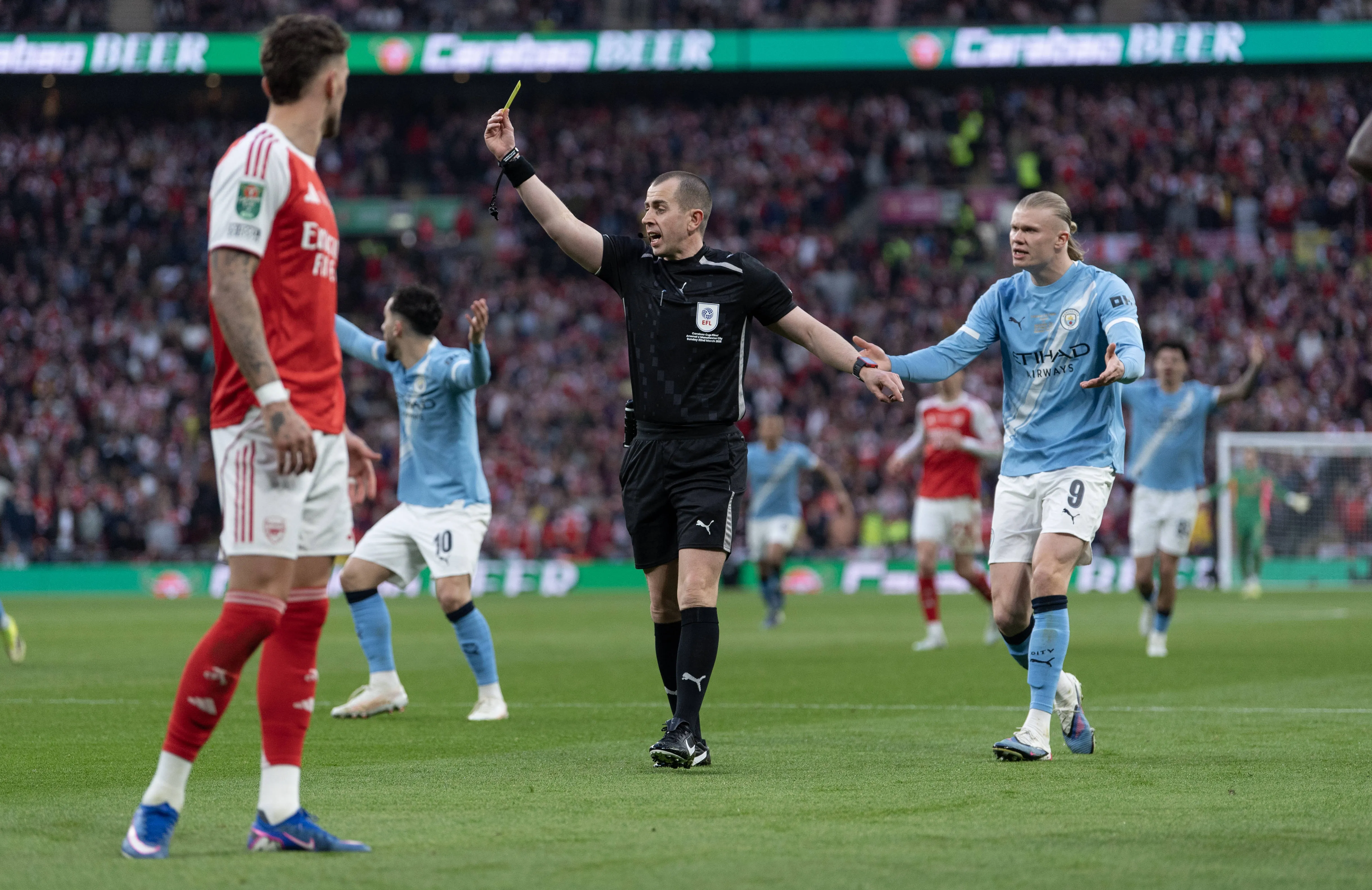 Referee Peter Bankes issues a yellow card during the Carabao Cup Final match between Arsenal and Manchester City