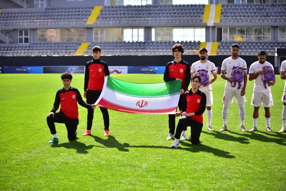 Iran players lineup beside country flag
