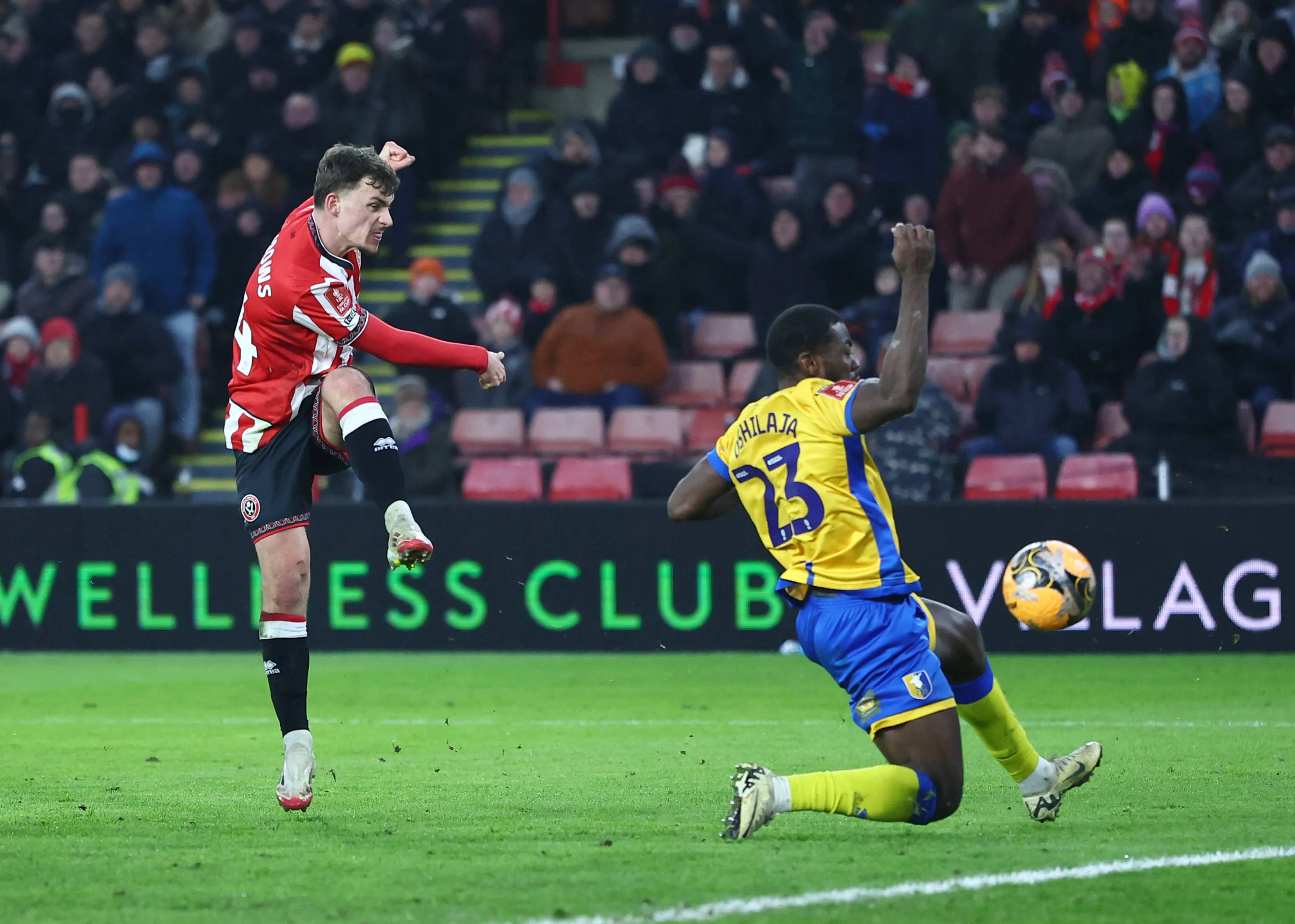 Harrison Burrows of Sheffield United has a shot blocked by Deji Oshilaja of Mansfield 