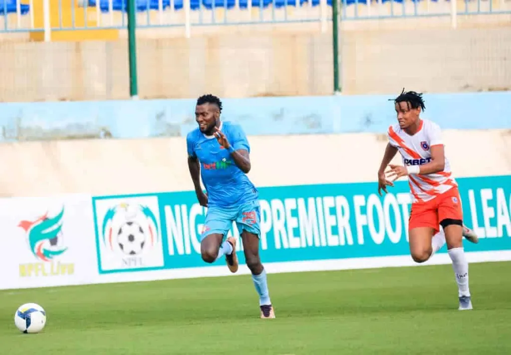 Sikiru Alimi (in blue) is marked by Akwa United defender Wisdom Ndon