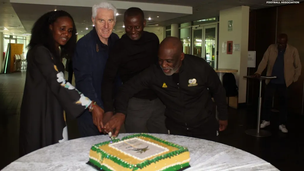 Hugo Broos cuts a cake to celebrate 2026 World Cup qualification.